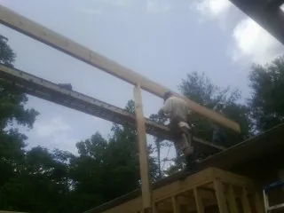 Carpenter setting a ridge beam over a new addition frame — Ice Dam Removal by Roofing Brothers in South Byron