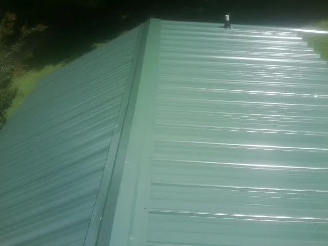 New green metal panels meeting at the ridge of a roof — Flat Roof Repair work by our crew in South Byron