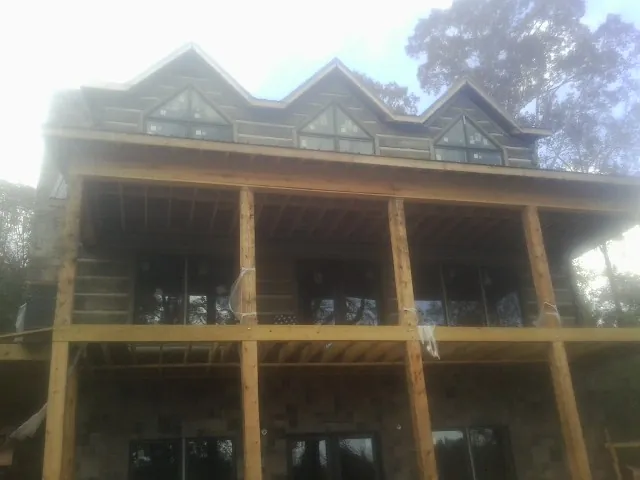 Dormers and porch framing on a large log home under construction — Roof Coating work by our crew in South Byron