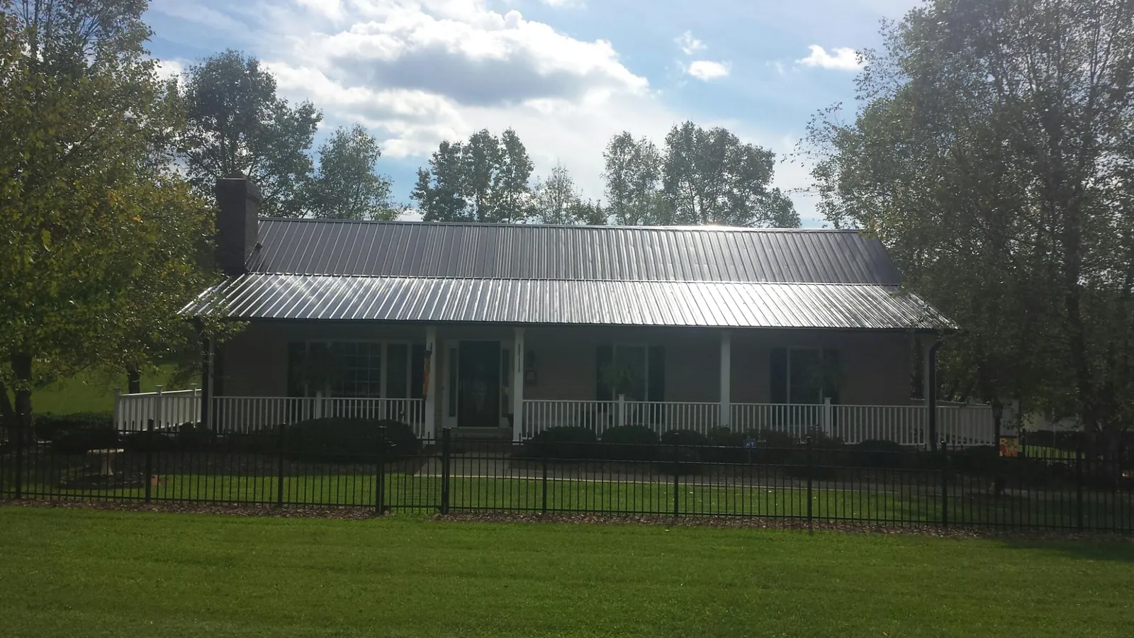 Gray metal roof on a brick ranch with a full width front porch — Gutter Guard Installation work by our crew in South Byron