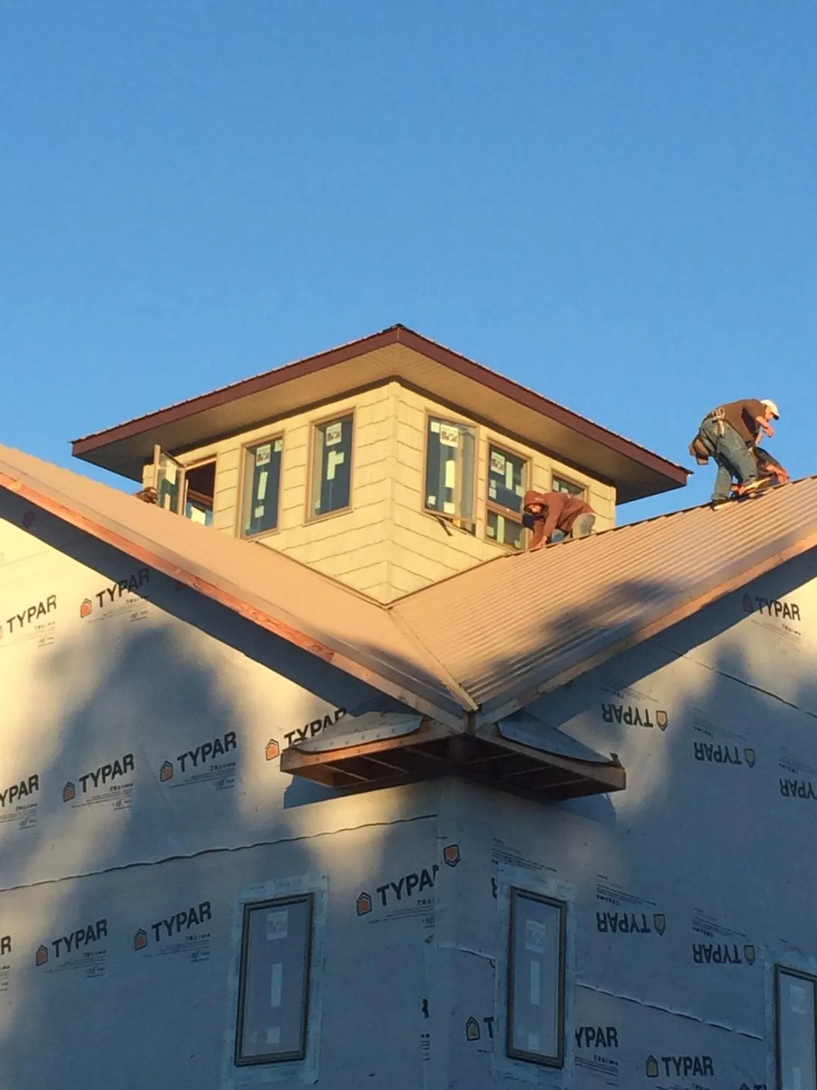 Roofers working around a rooftop cupola on a new metal roof at sunset — Roof Waterproofing in South Byron by Roofing Brothers